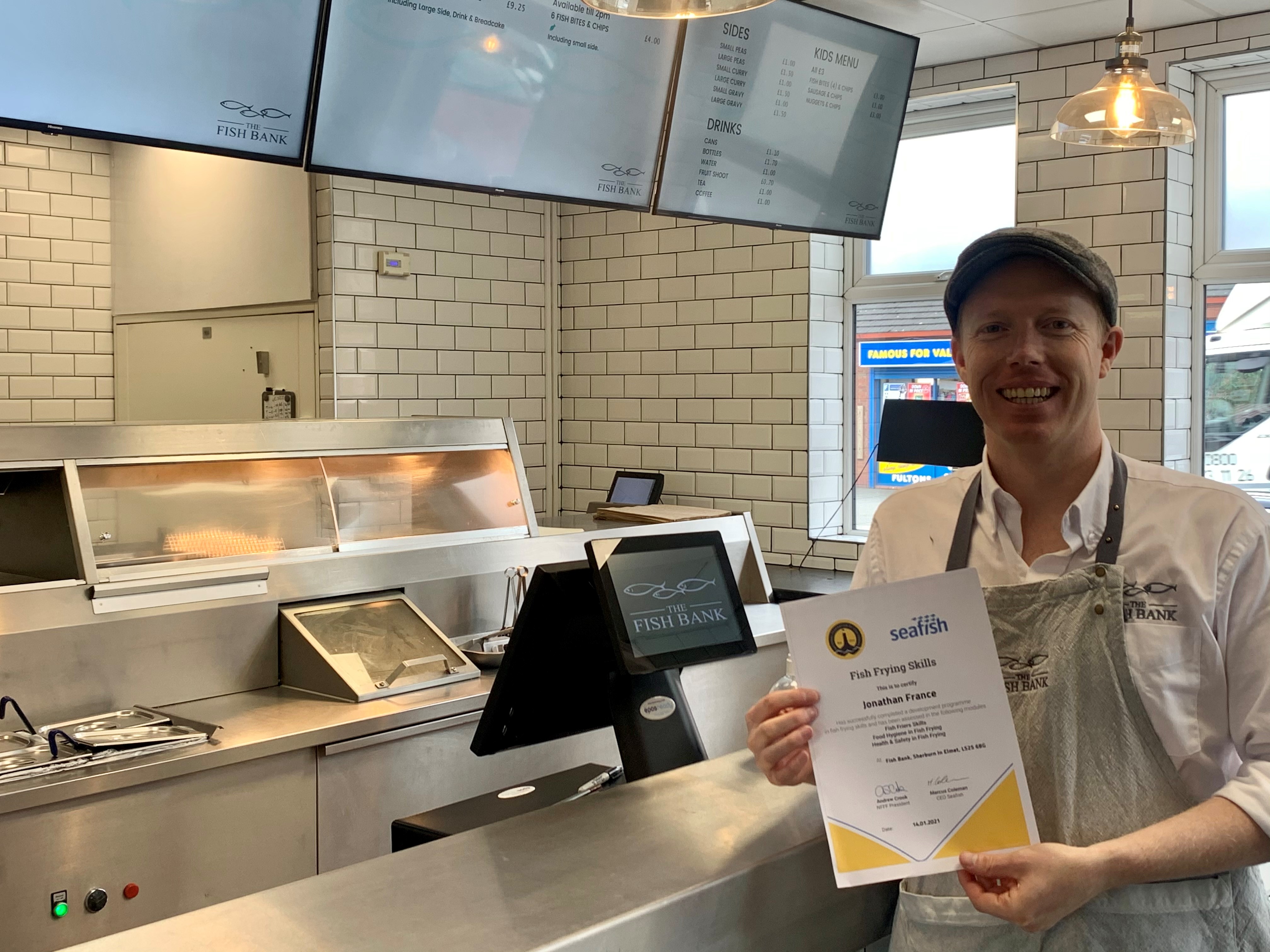 Jonathan France, fish frier, holding training certificate
